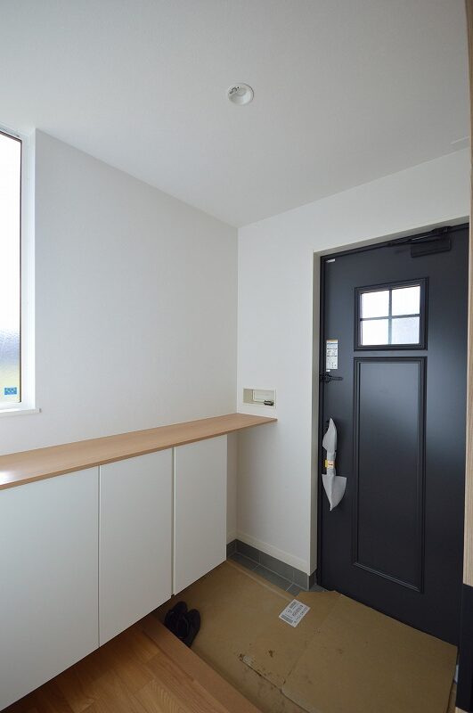 落ち着いた色合いの玄関スペース、収納力のある白いシューズボックス完備